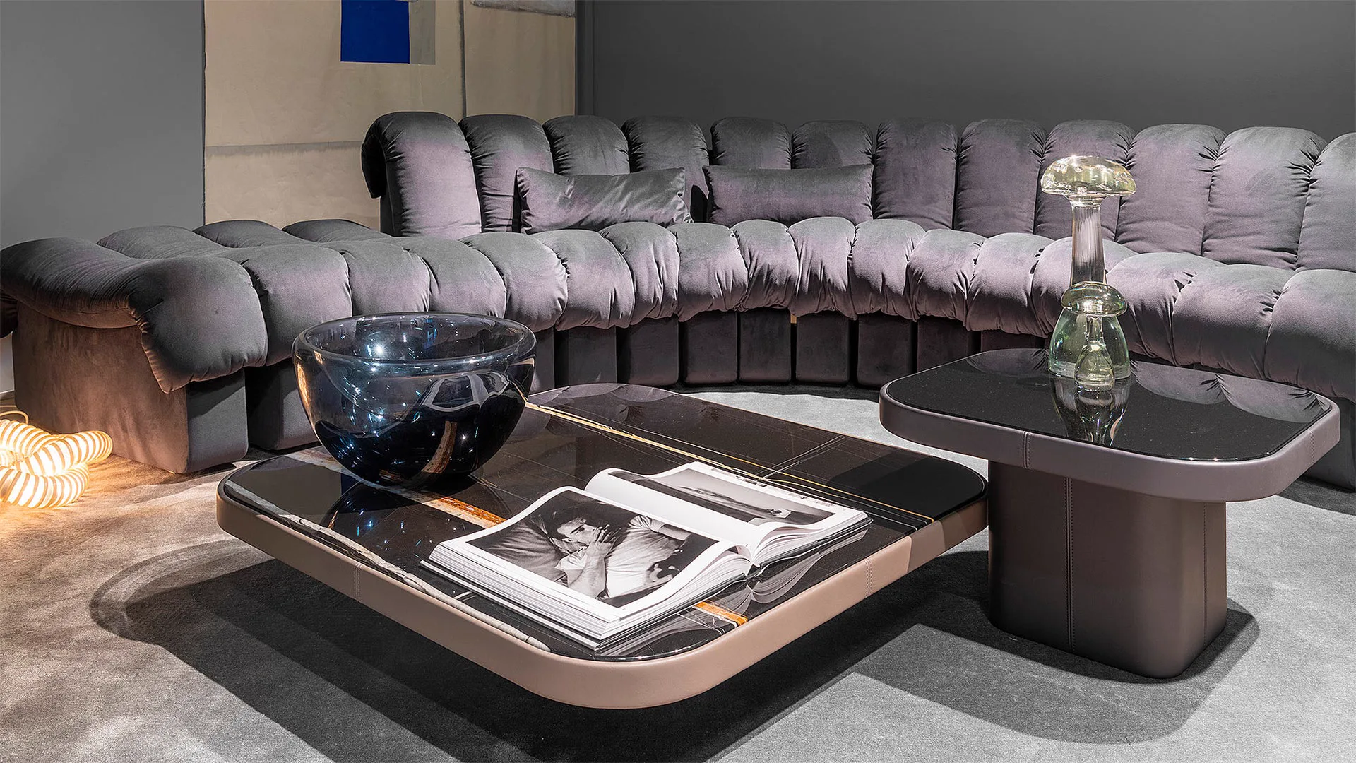 Graues Stoffsofa von Desede Switzerland mit schwarzem Glastisch und dekorativer Vase im Wohnzimmer.